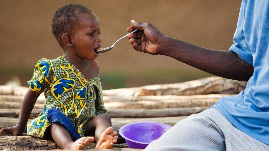 A Nigerian father feeding his daughter.