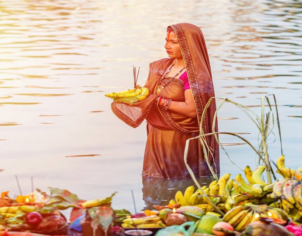 A woman worships Sun God as she celebrates Chhath Puja